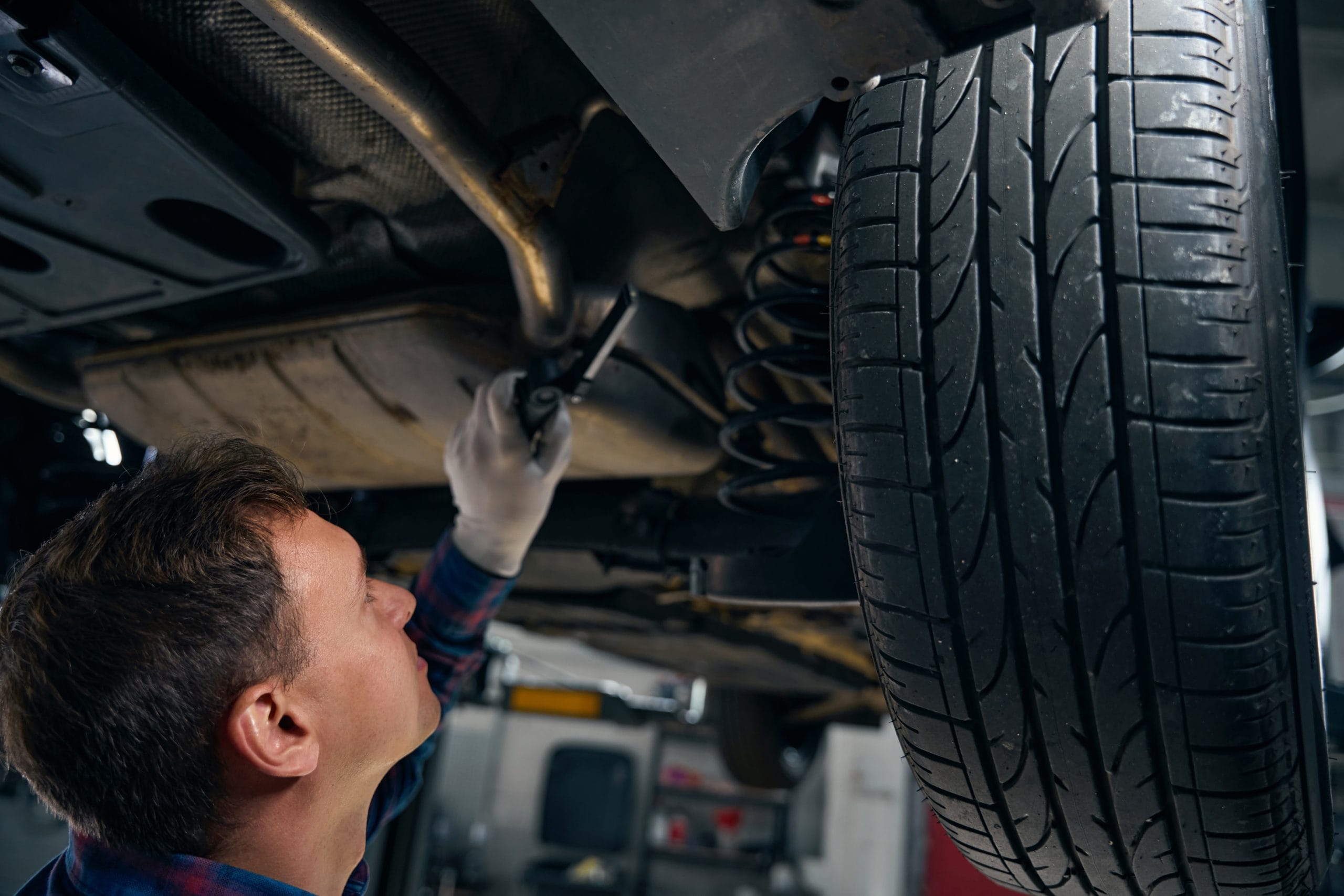 Man performing technical inspection of car suspension