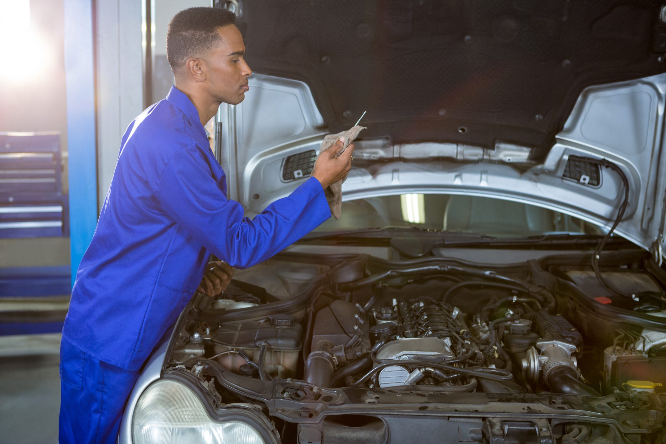 Mechanic wiping dipstick with napkin at repair garage